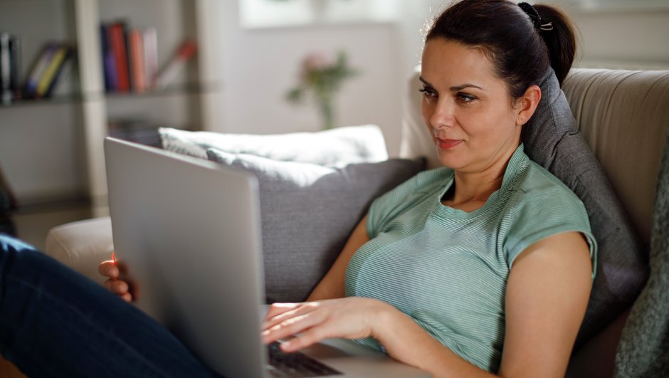 woman working with a laptop, sitting on sofa.