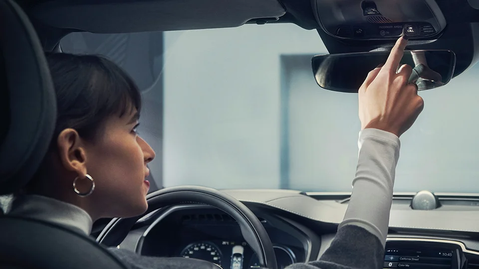 Kvinna trycker på Volvo on call-knapp i taket av bilen.