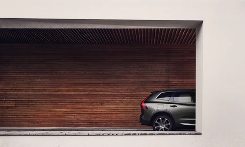 Volvo XC60 parkert ved brun trevegg