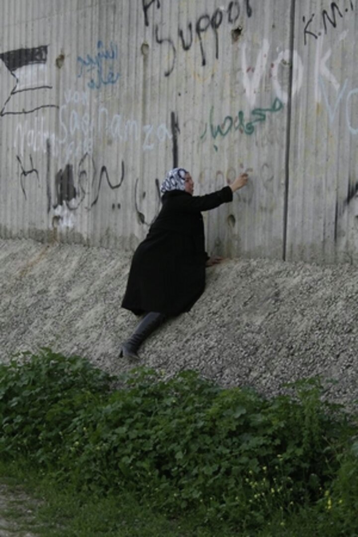 En palestinsk kvinne skriver på den 670 kilometer lange israelske muren som omgir det okkuperte Vestbredden.