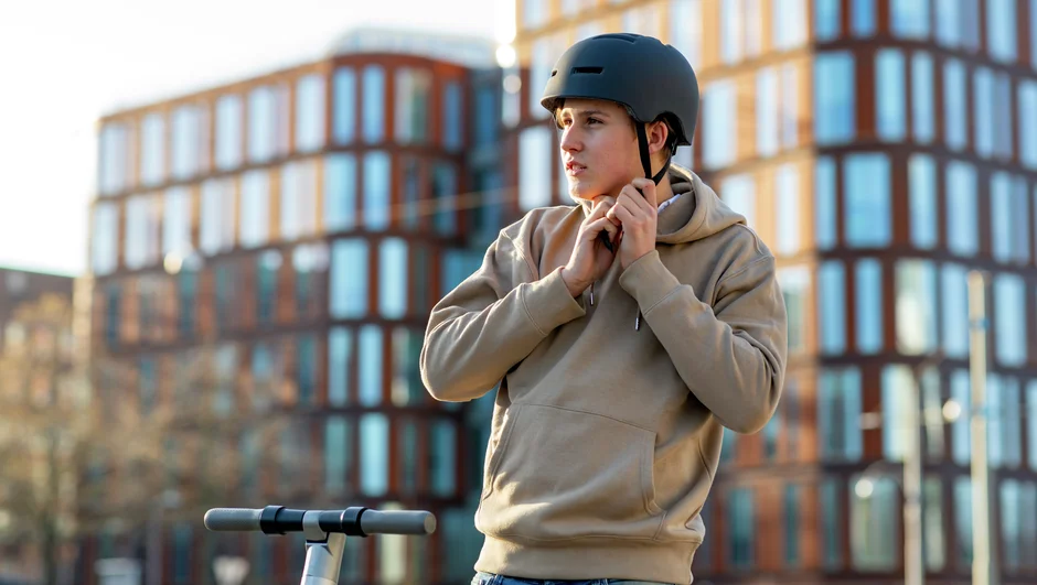 Gutt med sparkesykkel tar på seg hjelm