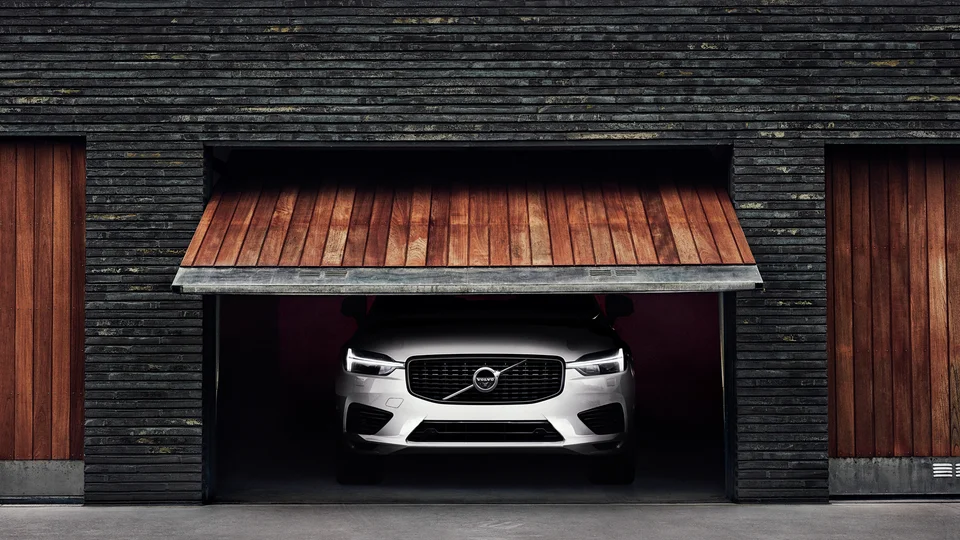 Silvrig Volvo XC60 parkerad i garage.