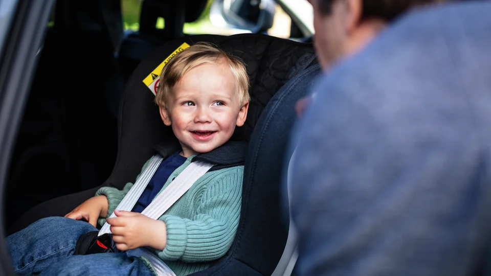 Pojke sitter fastspänd i bakåtvänd bilbarnstol.
