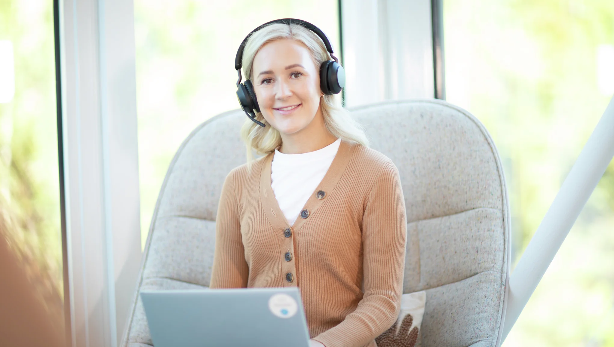 En smilende kvinnelig If-ansatt med headphones og en PC