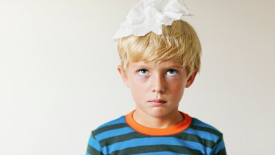 Ärsyyntynyt lapsi rutattu paperitollo päänsä päällä