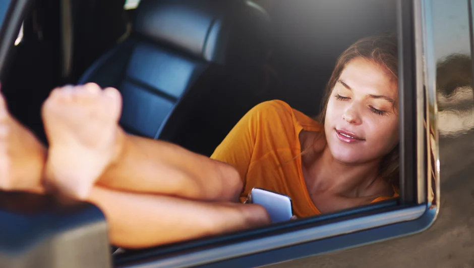 Kvinde sidder i en bil med benene ude af vinduet