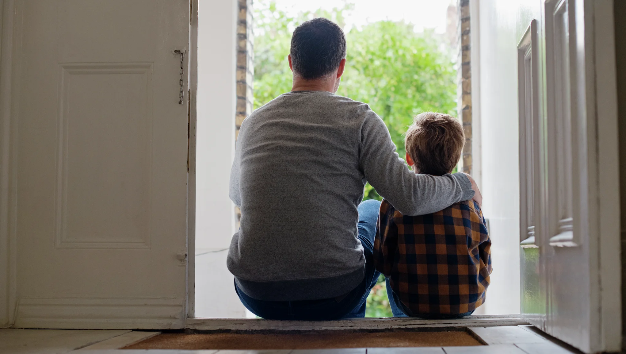 En far og sønn sitter på dørtrammen