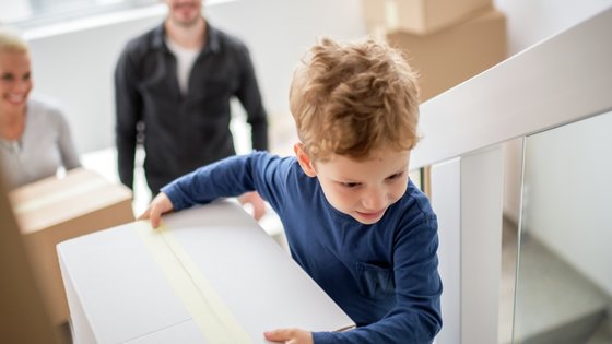 Lapsi kantaa muuttolaatikkoa portaissa