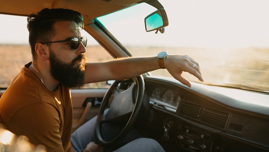Mand med solbriller på sidder i en bil