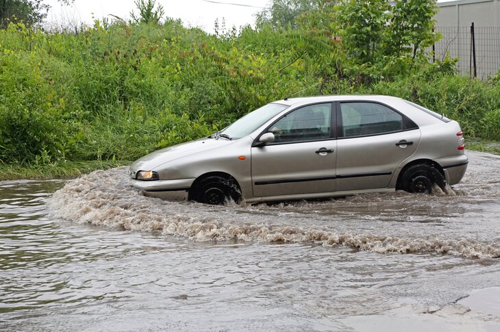 Bil kjører på oversvømt vei