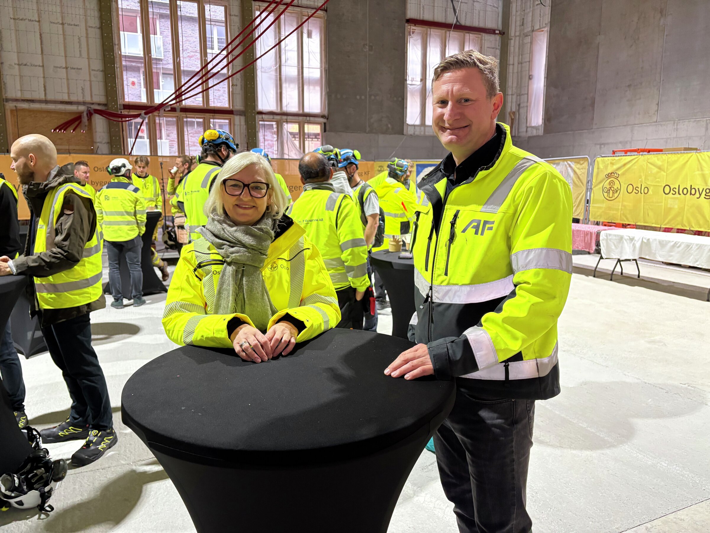 to personer i vernejakke inne på byggeplass