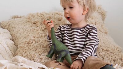 Lapsi leikkii muovidinosauruksella