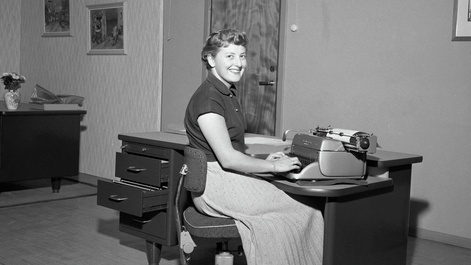 Kvinne ved skrivebord med skrivemaskin