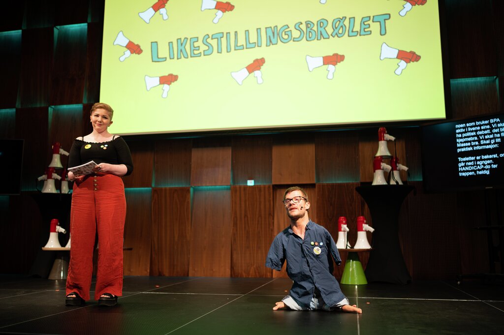 Mone Celin Skrede og Sebastian Tjoerstad på scenen under LIkestillingsbrølet 2021. De leder programmet og har talekort og mikrofoner.