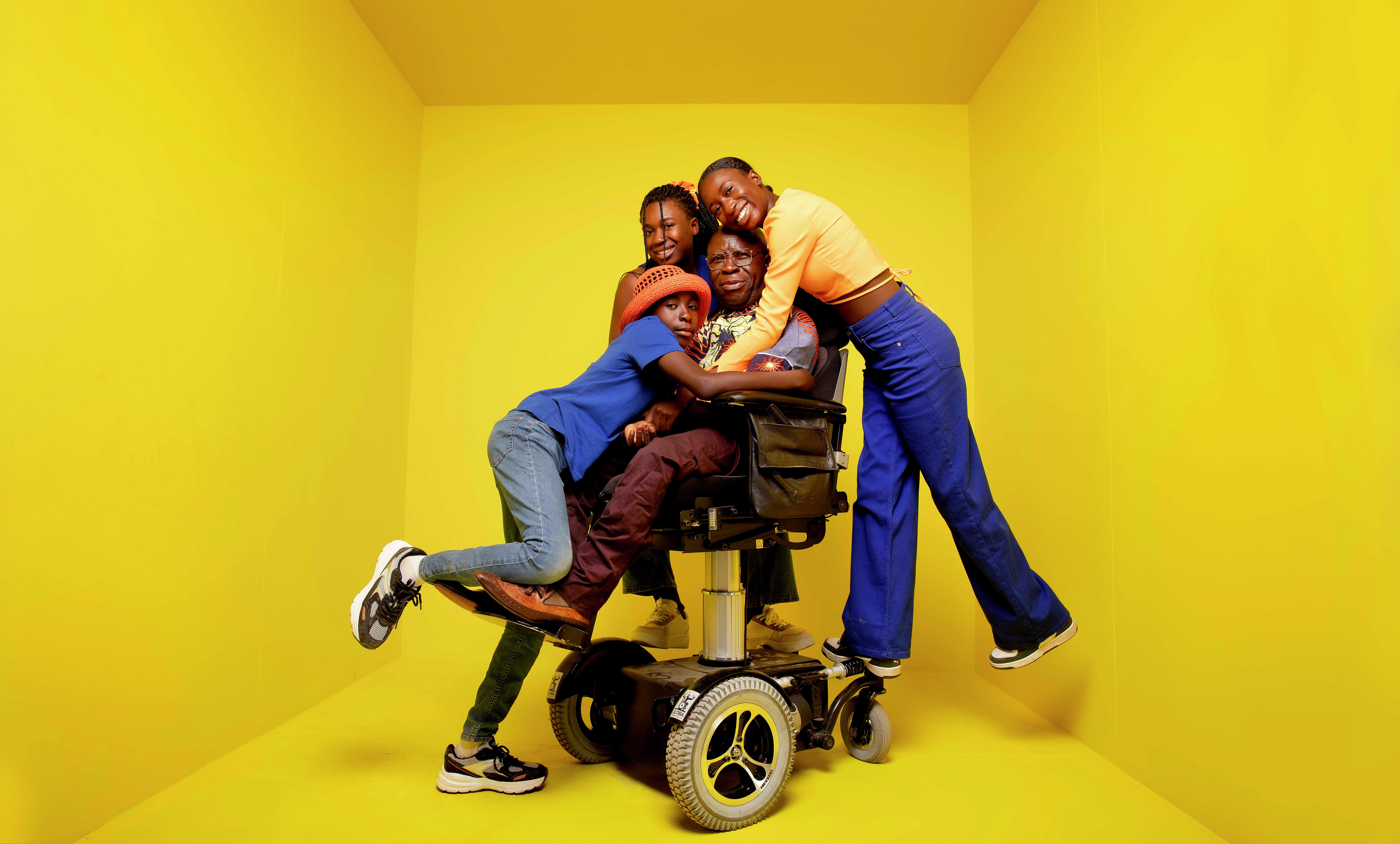 Bihayo og hans tre barn står å klemmer inne i en gul boks,