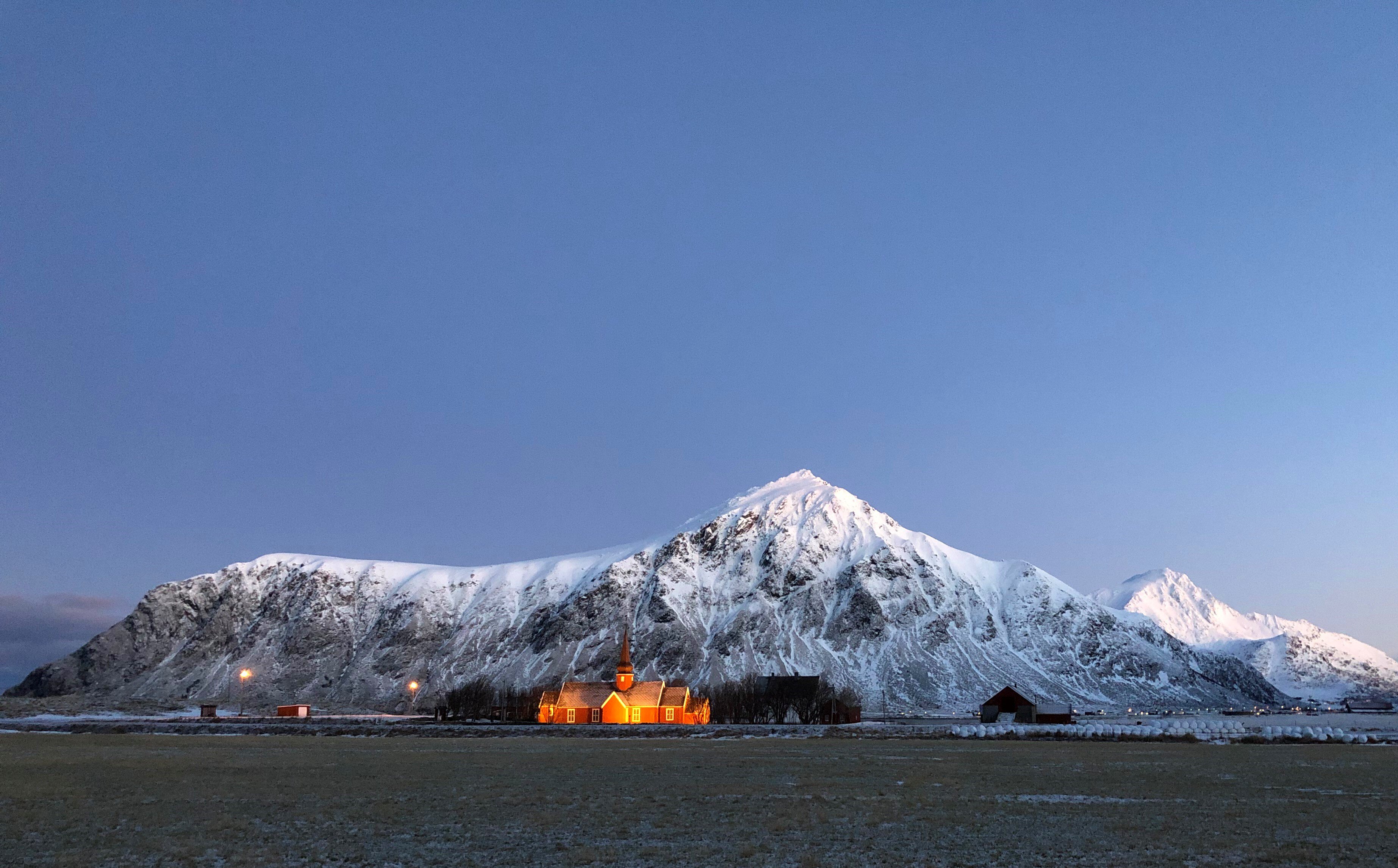 Flakstad church lit up with mountains behind