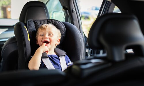 Pojke sitter fastspänd i bakåtvänd bilbarnstol