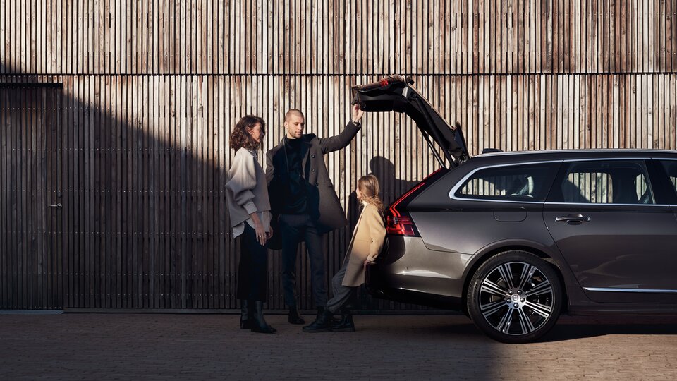 Familj står vid öppen baklucka till en Volvo V90