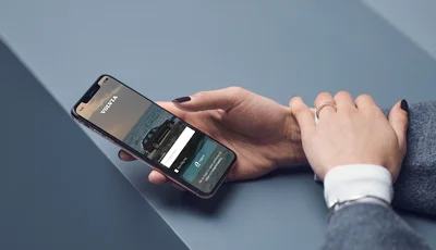 Hand håller i en smartphone med Volvia-appen.