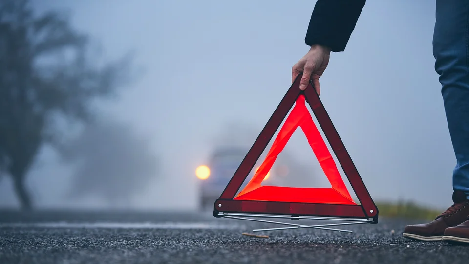 Person placerar ut varningstriangel på vägen efter singelolycka
