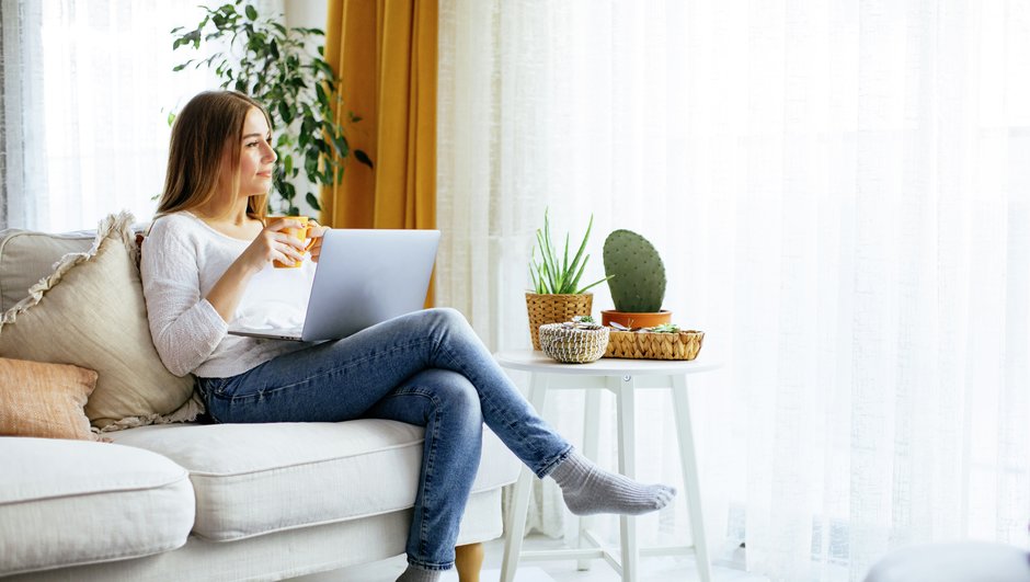Kvinna sitter i soffan med dator i knät