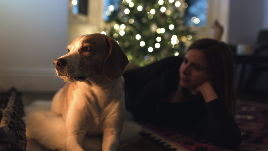 Kvinde og hund foran et juletræ