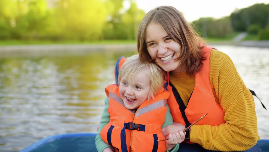 Smiling mother and child wearing life vest in a boat.