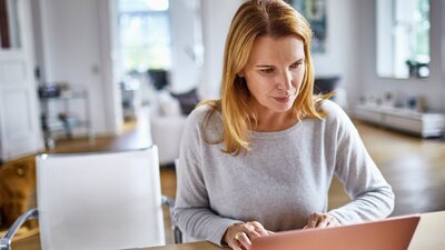 nainen tekee töitä kotona tietokone keittiön pöydällä.