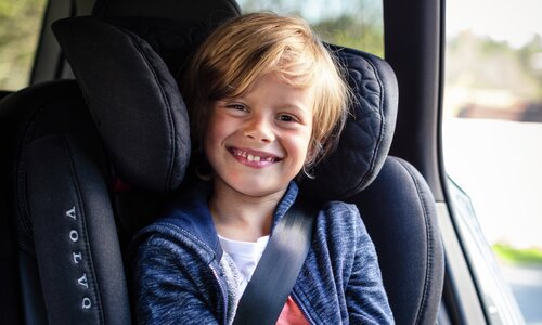 Leende pojke sitter i framåtvänd bilbarnstol